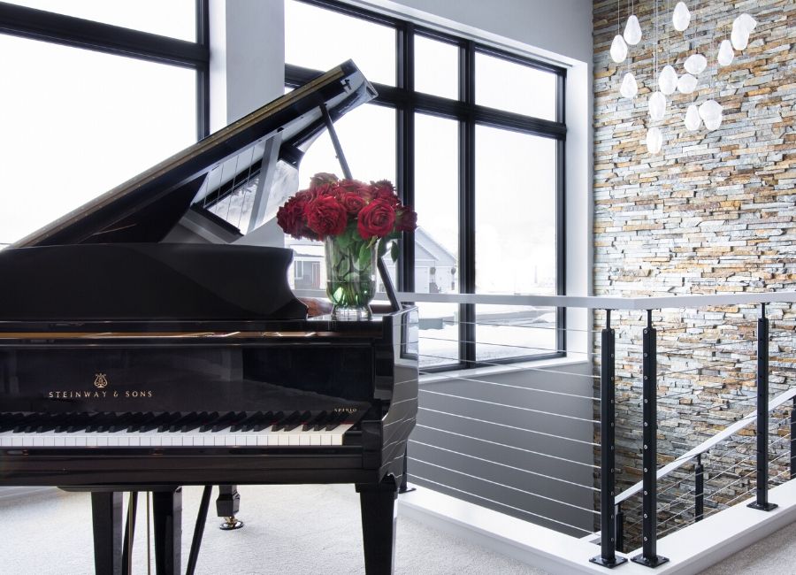 Grand Piano against large windows and stone veneer wall 